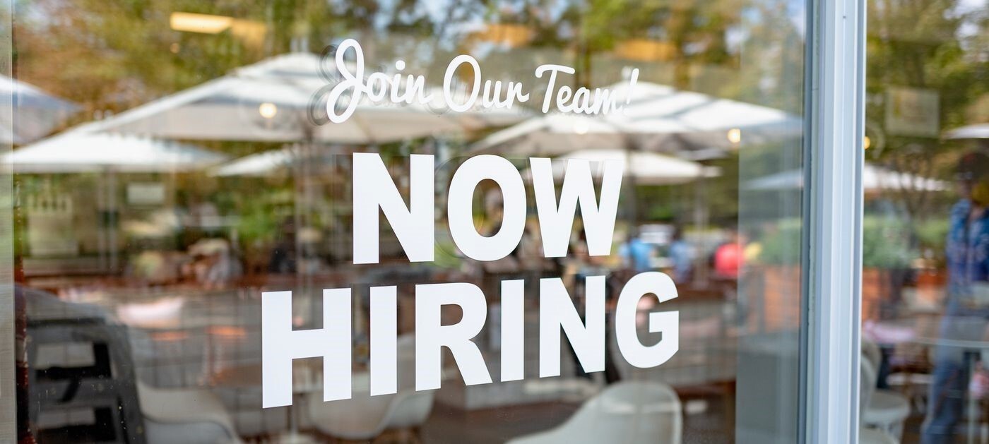 Window with a "now hiring" sign.